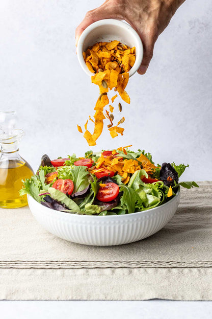 pouring zaxsnax on top of a salad